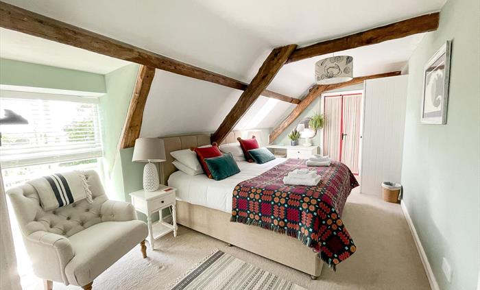 A superking bedroom with welsh tapestry blanket in red, orange and petrol blue. Seadog and stone self catering holiday let